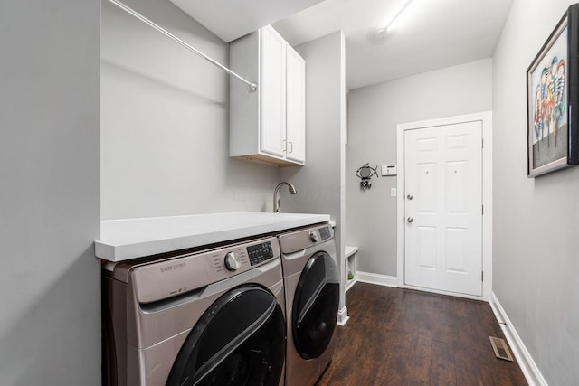 laundry area with cabinets, dark hardwood / wood-style flooring, and washer and clothes dryer