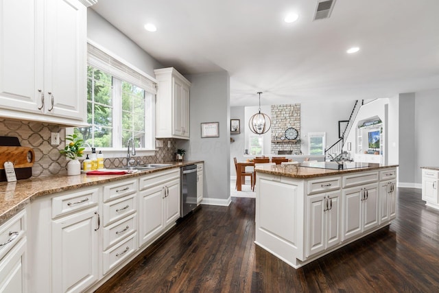 kitchen with dark wood-type flooring, white cabinets, hanging light fixtures, stainless steel dishwasher, and light stone countertops