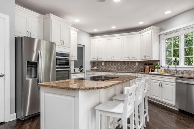 kitchen featuring white cabinetry, a center island, stainless steel appliances, light stone counters, and dark hardwood / wood-style floors