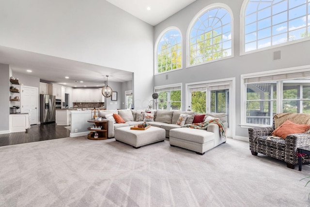 carpeted living room featuring a high ceiling and an inviting chandelier