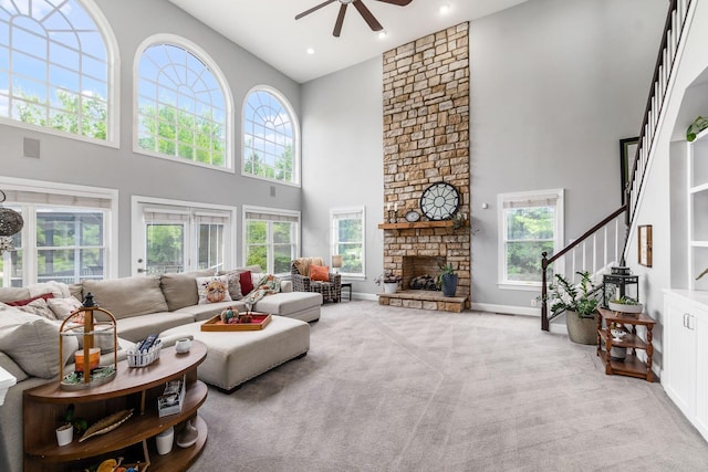 carpeted living room featuring a fireplace, a high ceiling, plenty of natural light, and ceiling fan