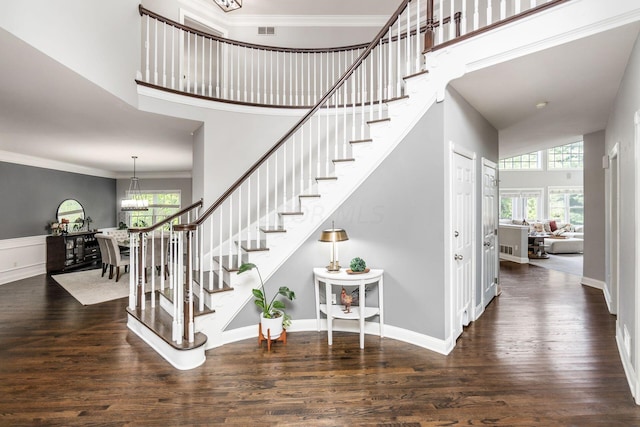 stairway featuring crown molding, plenty of natural light, hardwood / wood-style floors, and a high ceiling