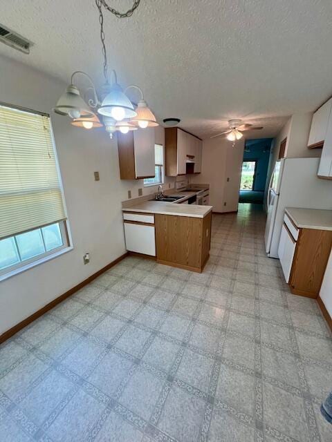 kitchen featuring sink, white appliances, ceiling fan, a textured ceiling, and kitchen peninsula