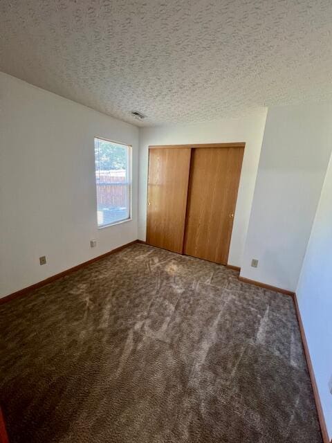 unfurnished bedroom featuring a closet, a textured ceiling, and carpet flooring