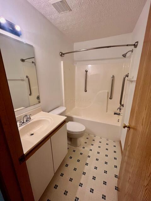 full bathroom featuring vanity, bathing tub / shower combination, a textured ceiling, and toilet