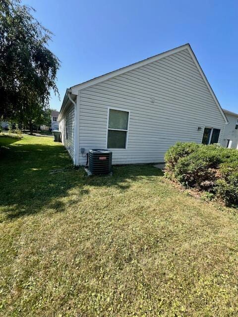 view of side of property with a lawn and central air condition unit