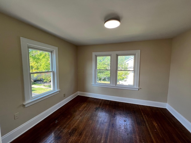 spare room featuring a wealth of natural light and dark hardwood / wood-style floors