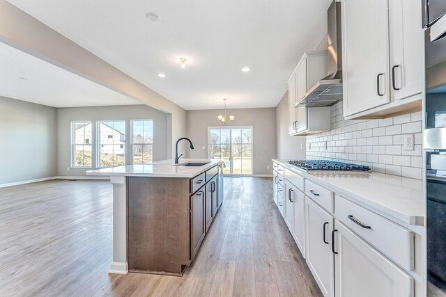 kitchen with white cabinetry, an island with sink, sink, and hanging light fixtures