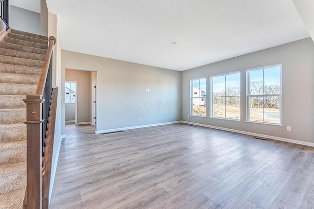 unfurnished living room with vaulted ceiling and light wood-type flooring