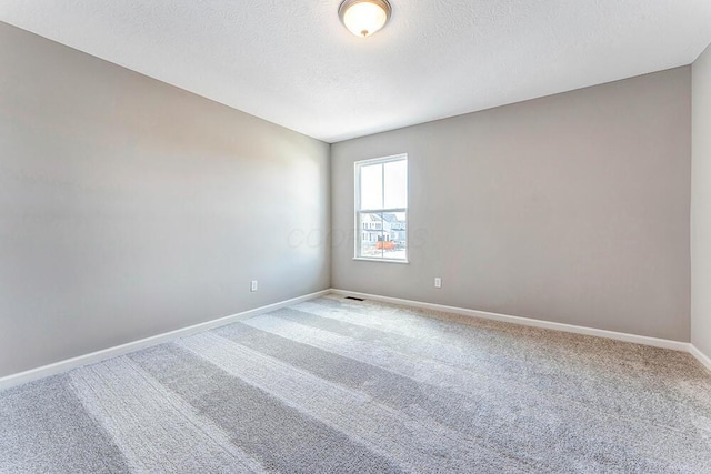 empty room with carpet and a textured ceiling