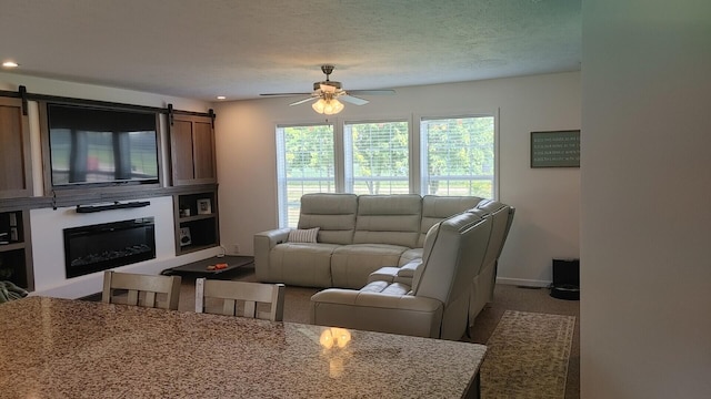 carpeted living room with ceiling fan and a textured ceiling