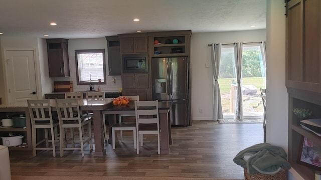 kitchen featuring stainless steel fridge with ice dispenser, dark hardwood / wood-style flooring, built in microwave, and a healthy amount of sunlight