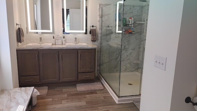 bathroom featuring decorative backsplash, wood-type flooring, vanity, and a shower with door