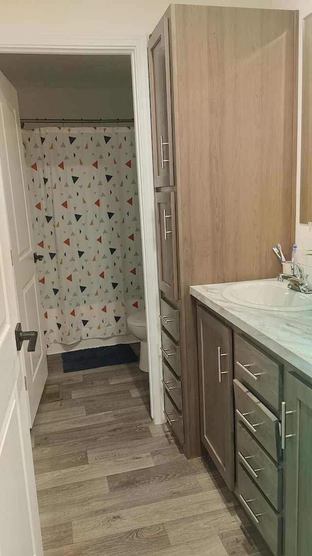 bathroom featuring wood-type flooring, vanity, and toilet