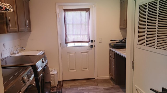 clothes washing area with cabinets, independent washer and dryer, light hardwood / wood-style floors, and sink