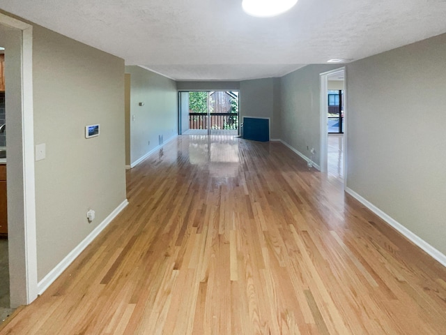 unfurnished living room featuring light wood-type flooring and a textured ceiling