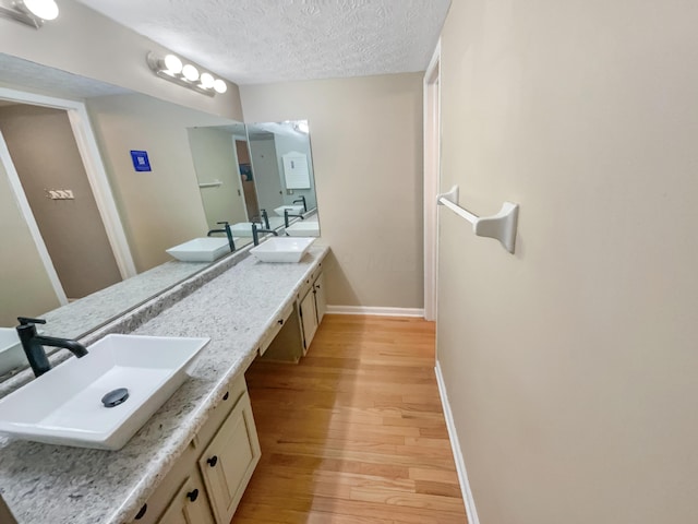 bathroom with hardwood / wood-style flooring, vanity, and a textured ceiling