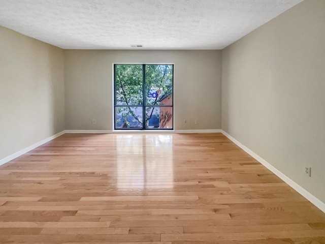 unfurnished room featuring light hardwood / wood-style floors and a textured ceiling