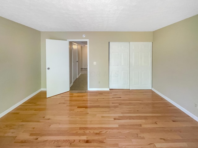 unfurnished bedroom featuring a closet, light hardwood / wood-style floors, and a textured ceiling