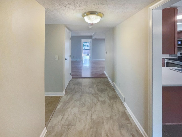 corridor with light hardwood / wood-style floors and a textured ceiling