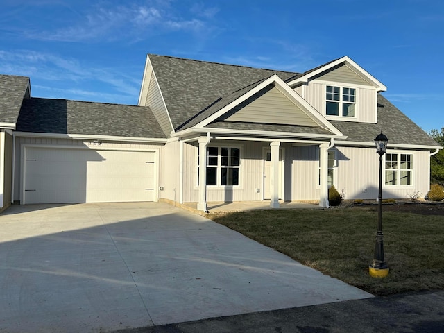 view of front of house featuring a front yard, a garage, and a porch