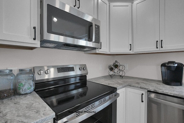 kitchen with light stone counters, white cabinets, and appliances with stainless steel finishes