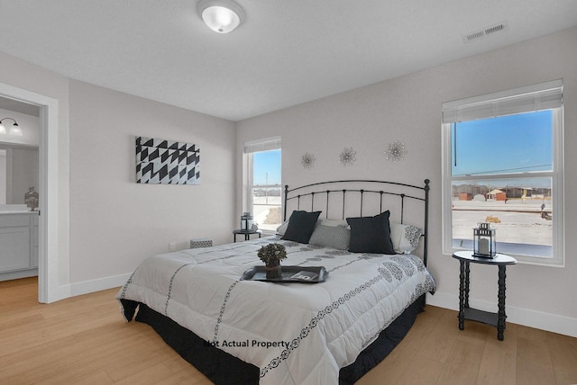 bedroom featuring connected bathroom and hardwood / wood-style flooring