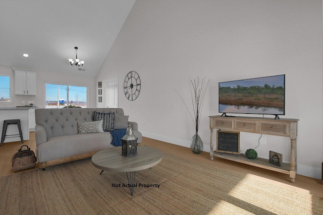 living room with light wood-type flooring, an inviting chandelier, and high vaulted ceiling