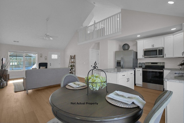 dining space with ceiling fan, high vaulted ceiling, and light hardwood / wood-style flooring