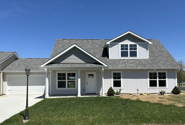 view of front of property with concrete driveway, roof with shingles, an attached garage, a porch, and a front lawn