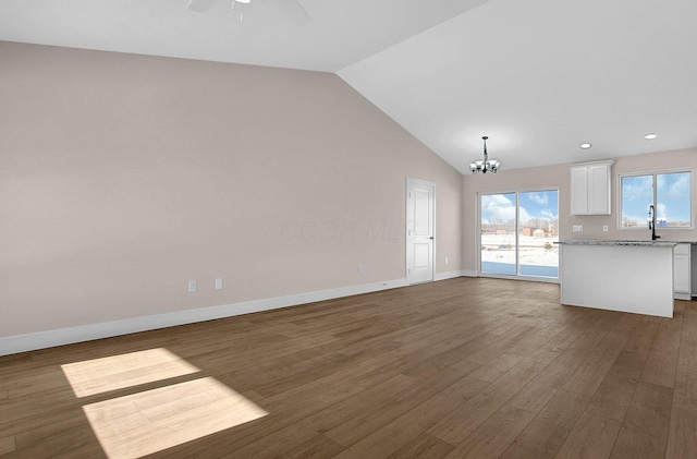 unfurnished living room featuring ceiling fan with notable chandelier, dark wood-type flooring, lofted ceiling, and sink