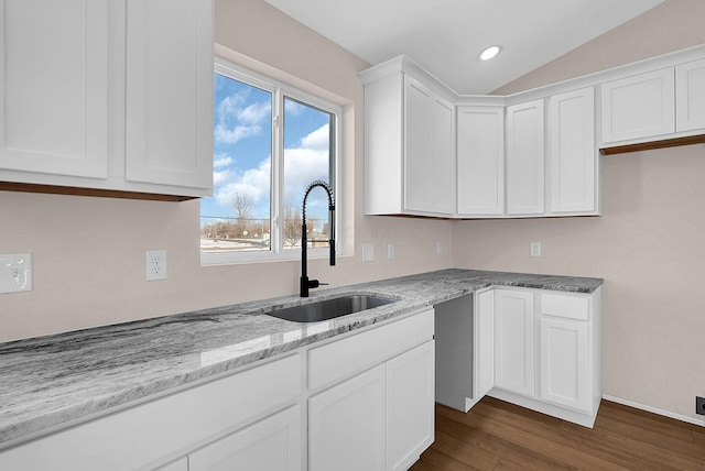 kitchen with light stone countertops, sink, white cabinetry, and lofted ceiling