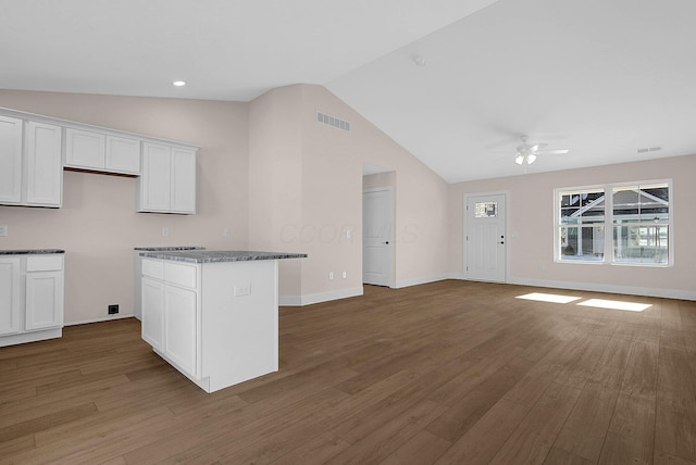 kitchen featuring ceiling fan, dark stone countertops, a center island, white cabinetry, and hardwood / wood-style flooring