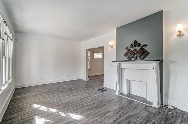 unfurnished living room featuring dark wood-type flooring and a brick fireplace