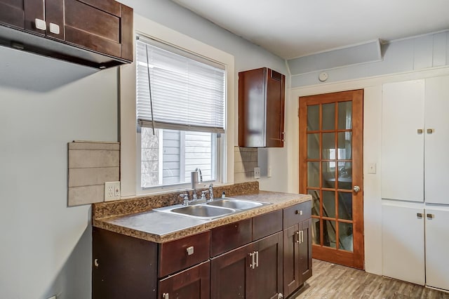 kitchen with decorative backsplash, dark brown cabinets, light hardwood / wood-style flooring, and sink