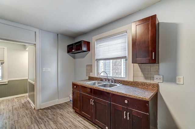 kitchen with tasteful backsplash, sink, and light hardwood / wood-style floors