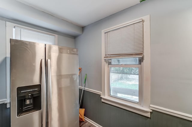 kitchen featuring stainless steel fridge with ice dispenser and wood walls