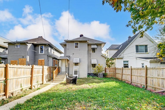 back of property featuring central AC unit and a lawn