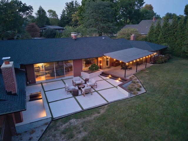 back of house featuring a yard, a shingled roof, outdoor lounge area, a patio area, and brick siding