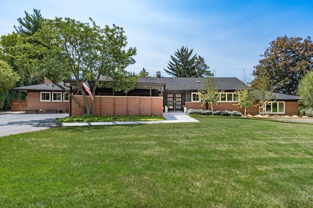 exterior space featuring brick siding, french doors, a front yard, and a chimney