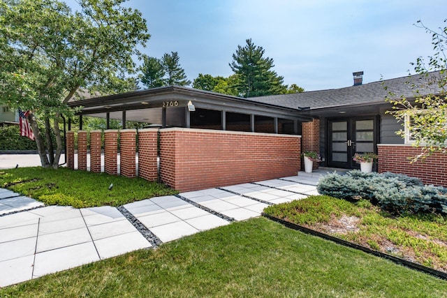 view of front of property featuring a front yard, french doors, and brick siding