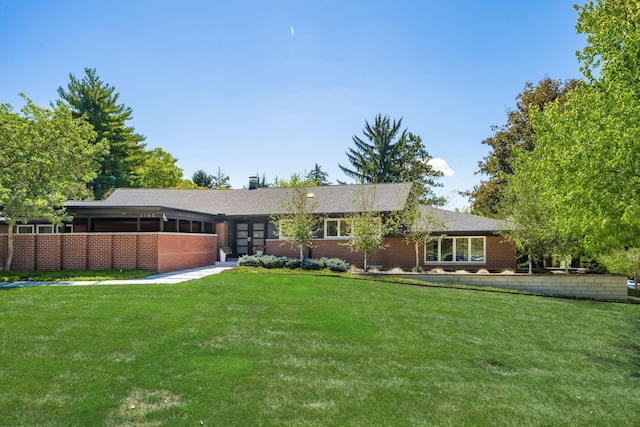 view of front of house with a front yard, brick siding, and a sunroom