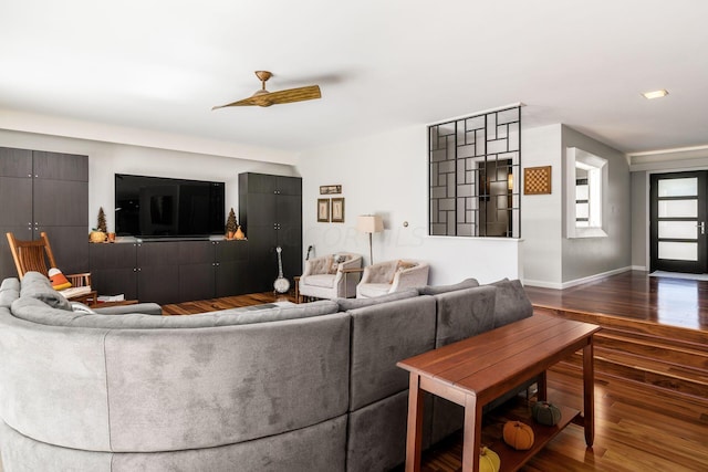 living area with ceiling fan, baseboards, and dark wood-style floors