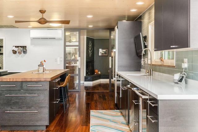 kitchen with beverage cooler, dark wood finished floors, a sink, a wall mounted air conditioner, and butcher block counters