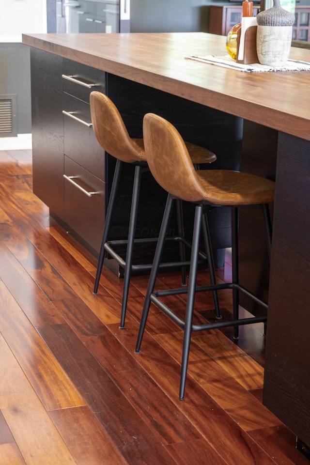 bar with visible vents, a dry bar, and wood-type flooring