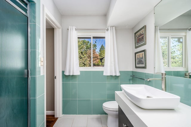 bathroom featuring toilet, tile walls, and vanity