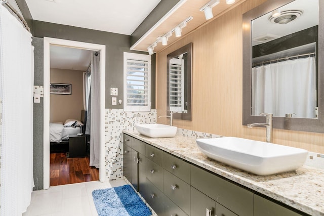 ensuite bathroom with ensuite bath, double vanity, tile patterned floors, and a sink