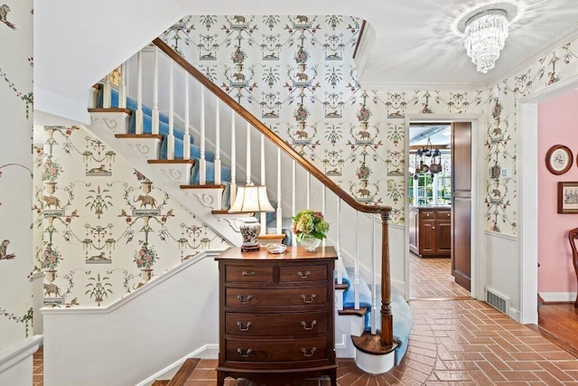 stairs with a notable chandelier and ornamental molding