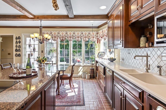 kitchen featuring decorative backsplash, sink, an inviting chandelier, hanging light fixtures, and stainless steel microwave