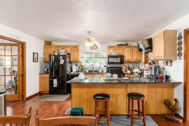 5595 Lancaster Rd, Hebron, OH 43025 - kitchen featuring kitchen peninsula, dark hardwood / wood-style flooring, and black appliances